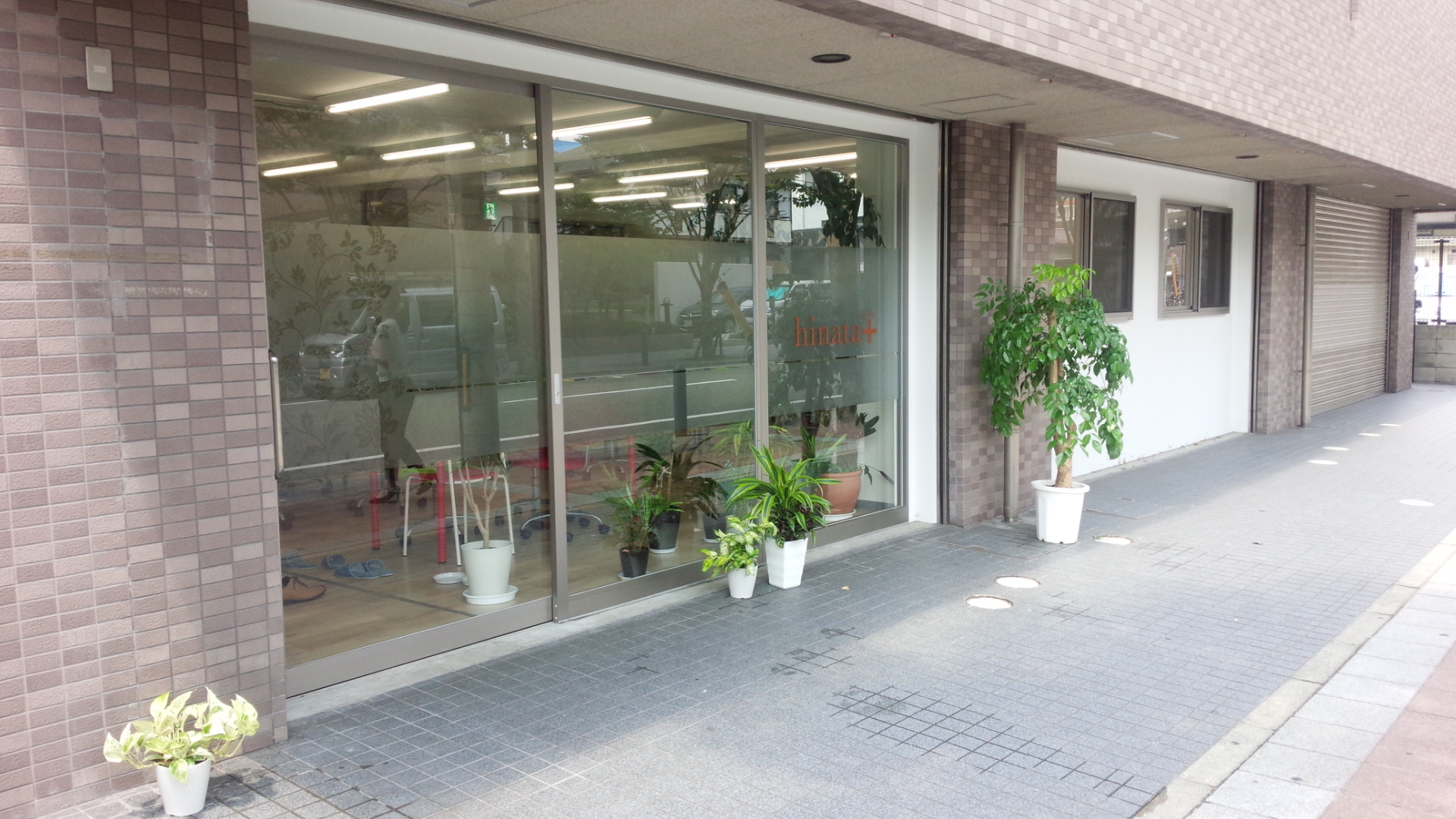 歩道に鉢植えの植物が並ぶ店舗の外観。アライズが運営する就労継続支援A型事業所の一つ。