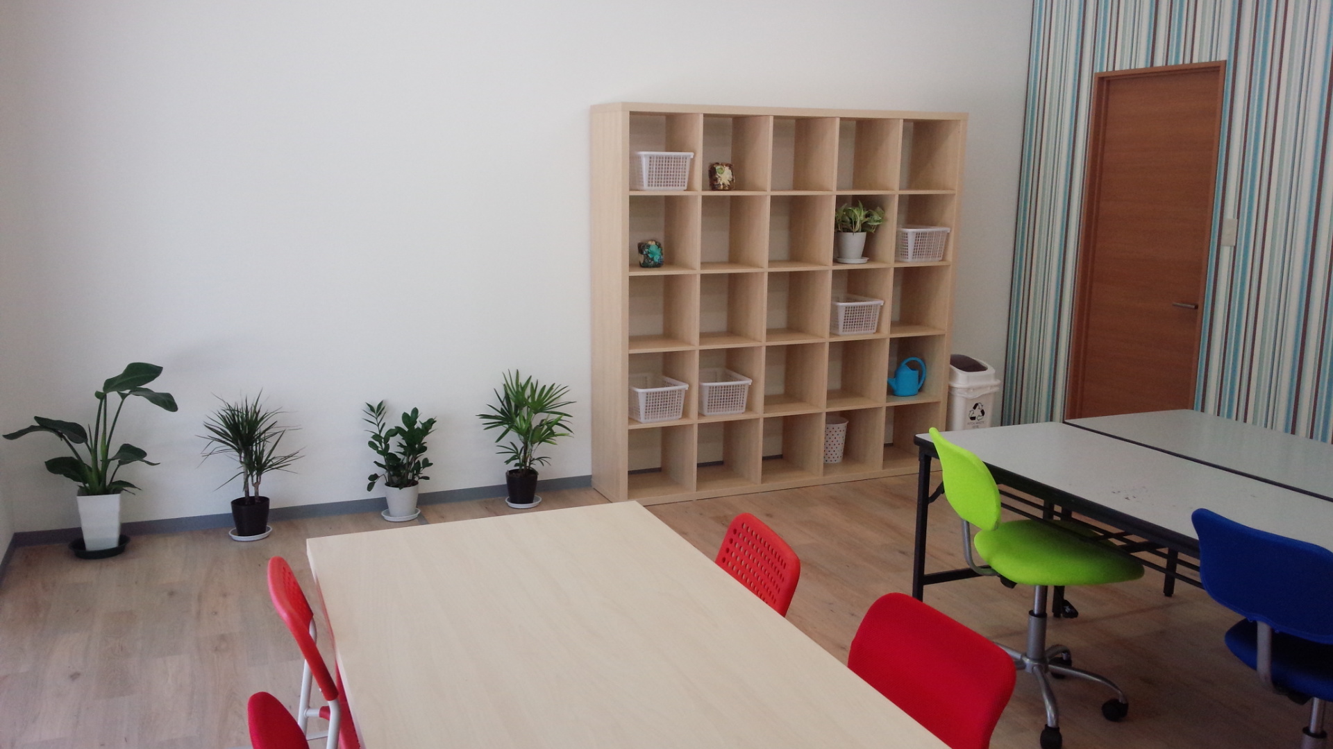 テーブル、椅子、本棚がある部屋の風景。㈱アライズが運営する就労継続支援A型事業所の一部。