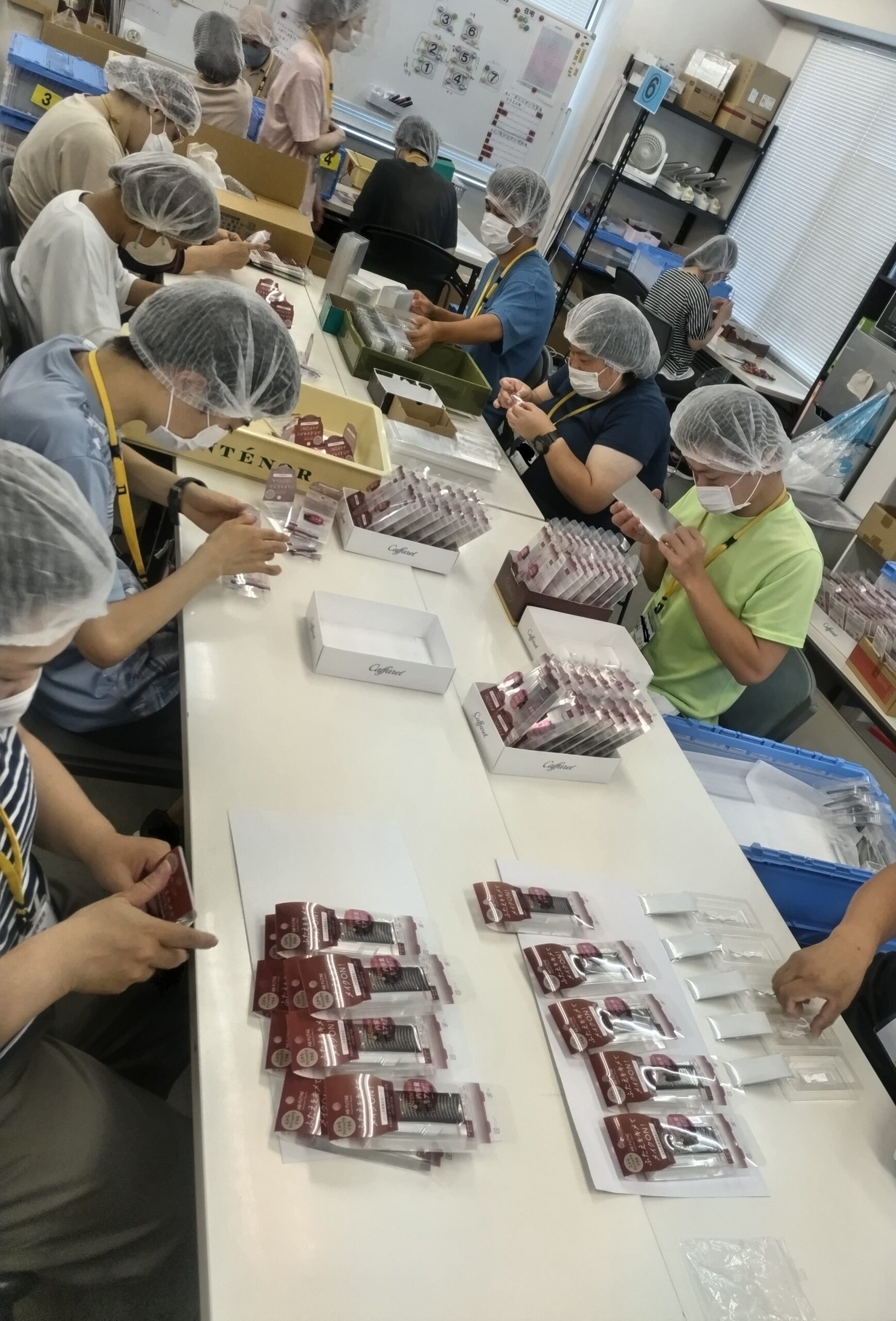製品の組み立て作業をしている工場内の人々の様子を示す画像です。