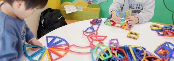 カラフルなプラスチックのおもちゃで遊ぶ二人の子供。児童発達支援・放課後等デイサービスの一環。